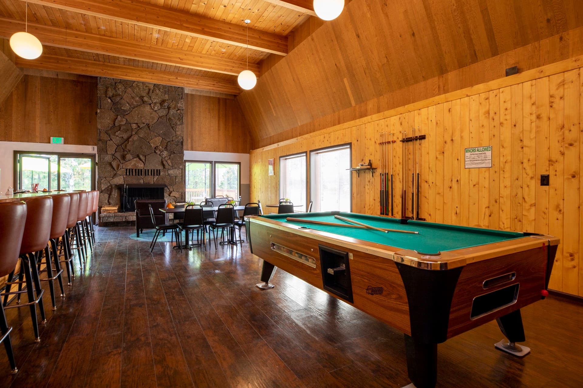 Clubhouse interior with pool table, bar, and stone fireplace at Round Lake Community